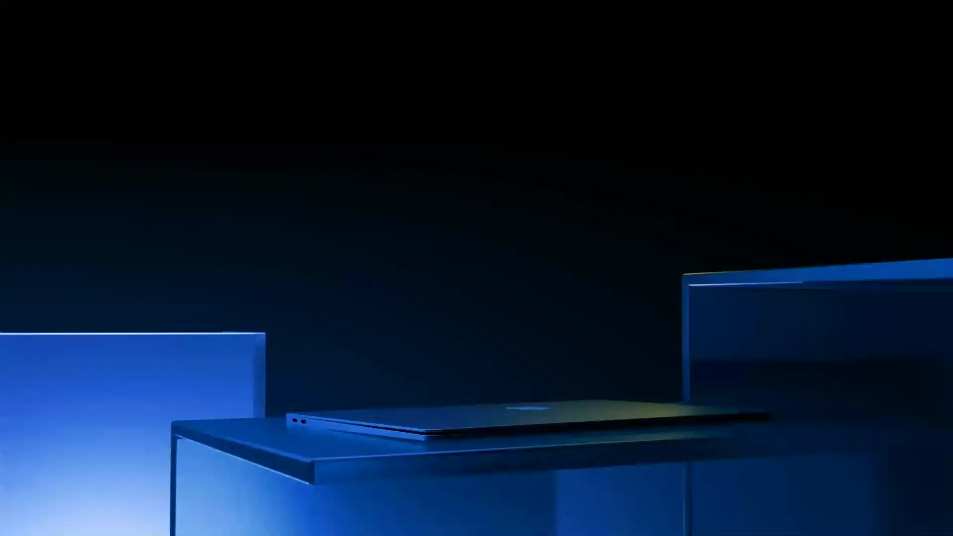 A laptop on a studio plinth, lit in deep blue