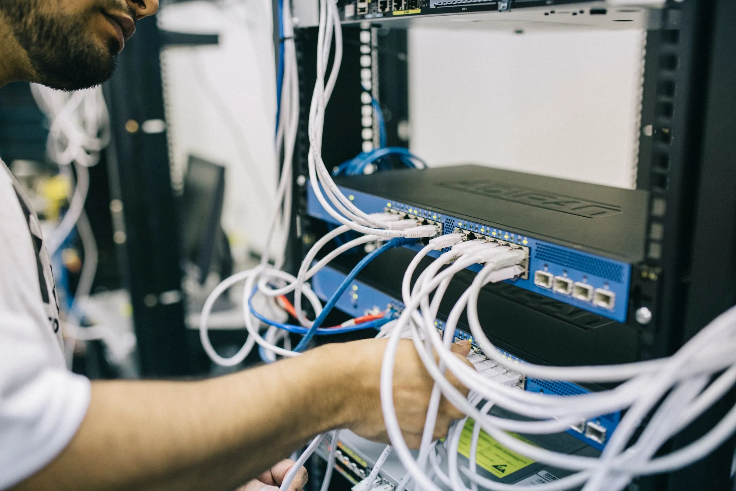 An engineer connecting network cables to a rack-mounted switch